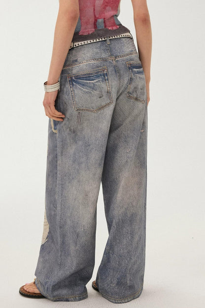 Jeans a gamba larga con stampa effetto strappato e look a strati