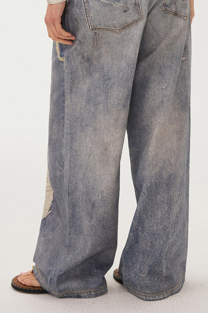 Jeans a gamba larga con stampa effetto strappato e look a strati