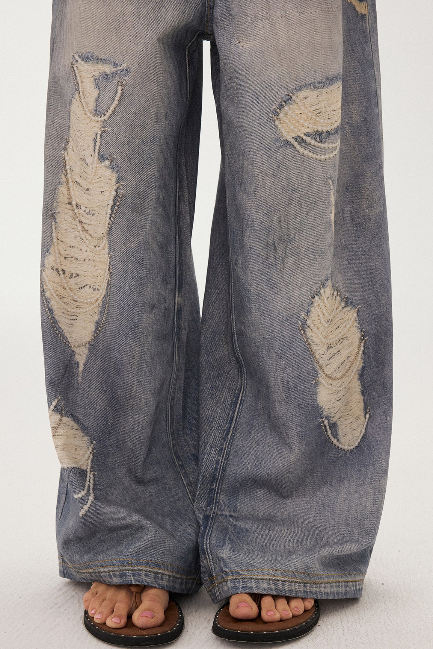 Jeans a gamba larga con stampa effetto strappato e look a strati