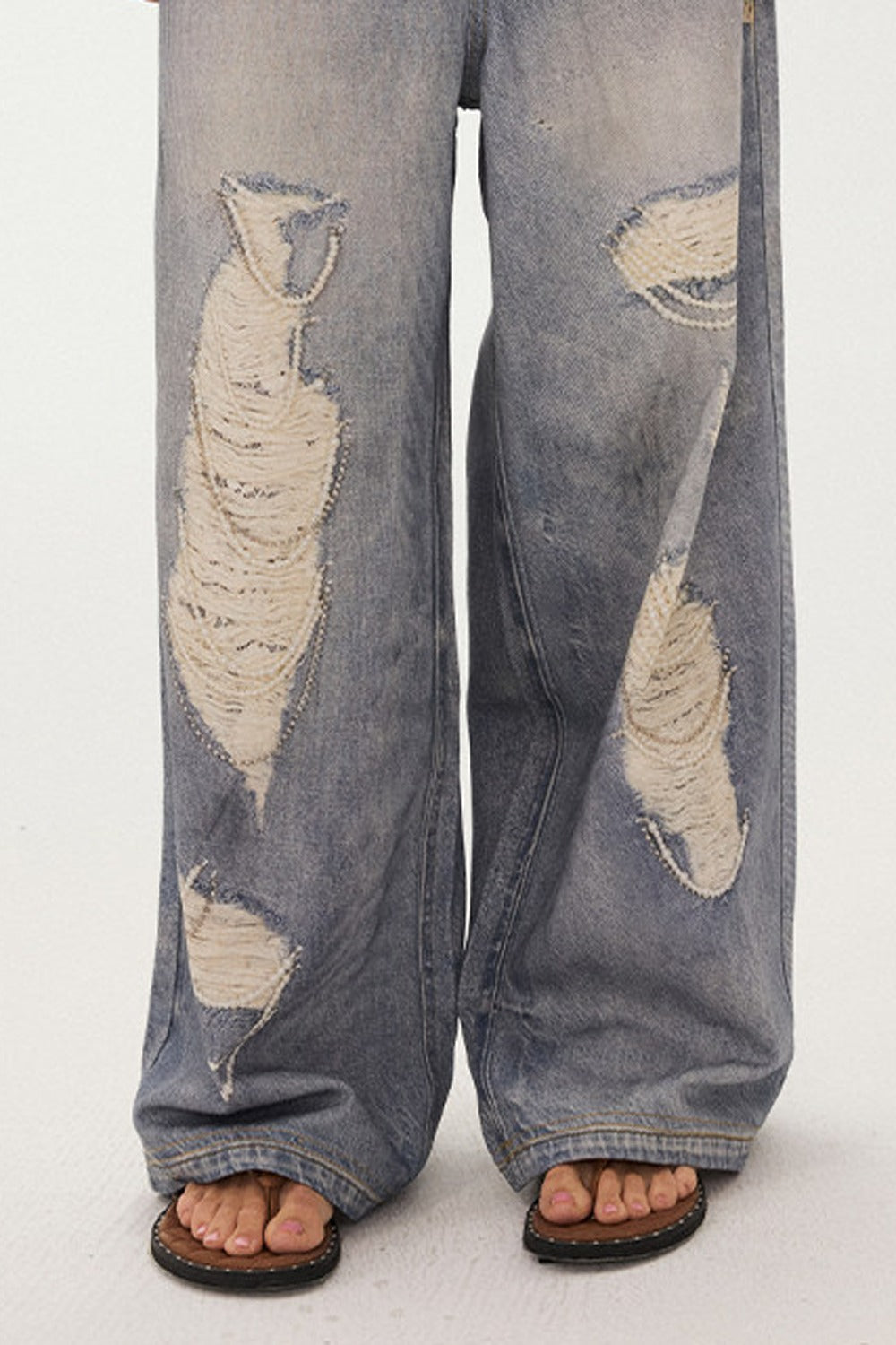 Jeans a gamba larga con stampa effetto strappato e look a strati